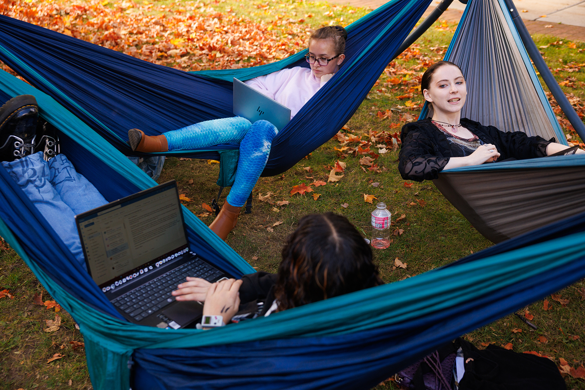 Three students doing their work outside on campus.